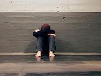 Person huddled next to a wall