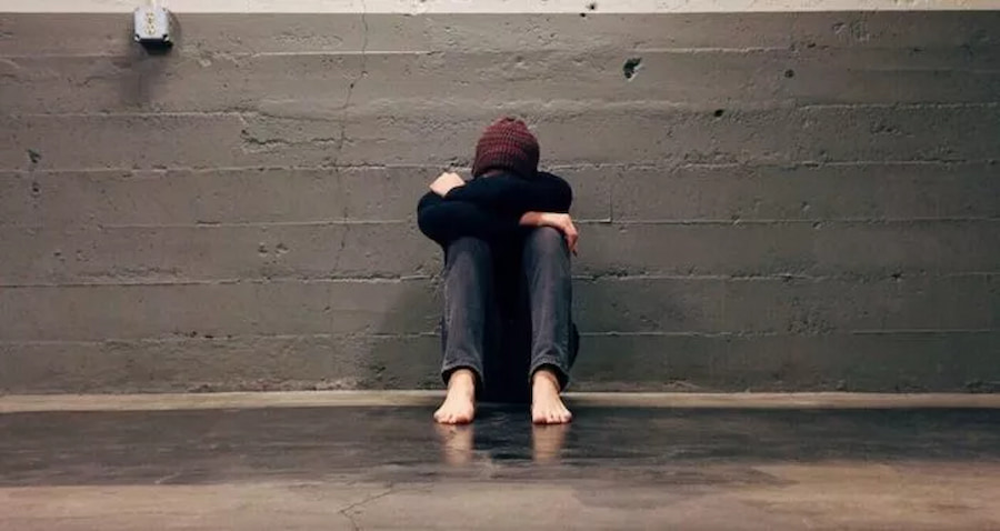 man huddled next to wall