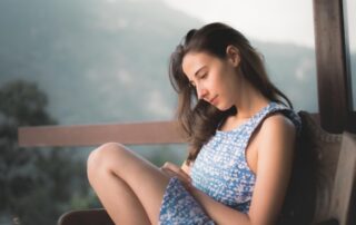 a-woman-sitting-on-a-bench-looking-at-her-cell-phone