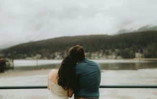 a-man-and-a-woman-sitting-on-a-bench-looking-at-a-lake
